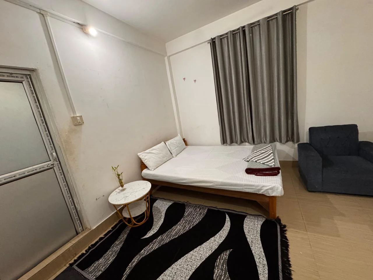 Guest room at Aana Pema Homestay with a bed, side table, curtains and armchair